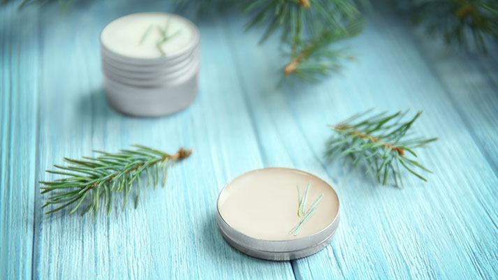 Cream and pine branches on wooden background