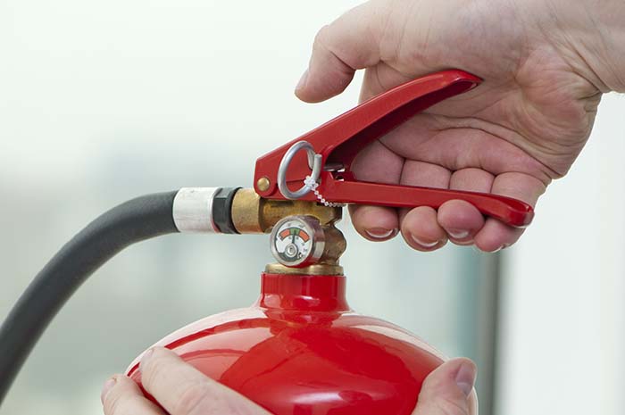 hand presses the trigger fire extinguisher